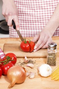 closeup of hands cutting tomatoes on a chopping board for italian food