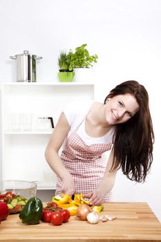 happy woman in a kitchen cutting yellow paprika for salad