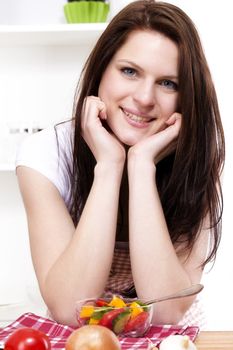 smiling young woman in kitchen with a small mixed salad