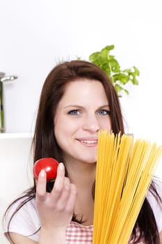 portrait of a happy young woman holding spaghetti and tomato