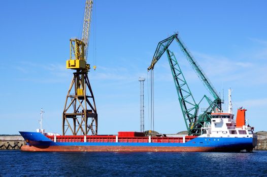 The cargoship and the crane on a background of the blue sky