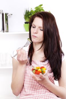pretty young woman about to eat salad in her kitchen