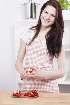 happy young woman working in the kitchen cutting paprika