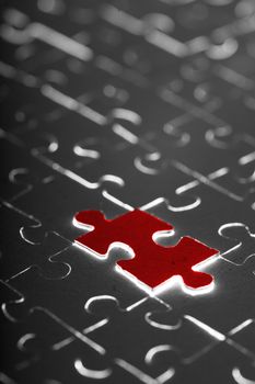 black puzzle with one red piece
