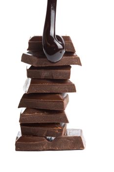 chocolate syrup being poured onto chocolate pieces isolated

