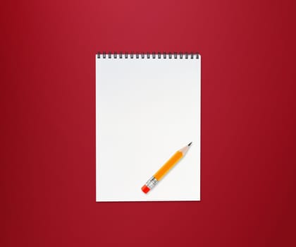 Notebook and small yellow pencil with eraser on red background