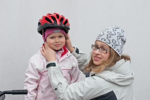 Mother puts in front of a girl riding a bicycle helmet.