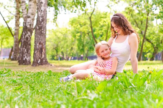 mother and daughter sitting together on the grass, and spend time with family