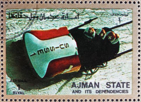 AJMAN - CIRCA 1973: a stamp printed in the Ajman shows Four-man Bobsled, Winter Olympics, circa 1973