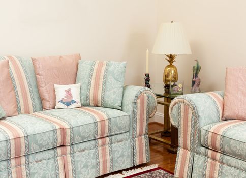 Modern living room with green and pink settees, glass table