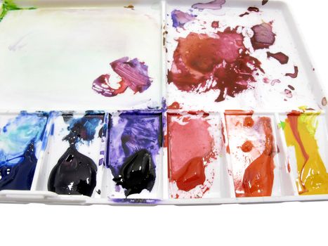 Paintbrush on white art palette with blobs of paint on white background