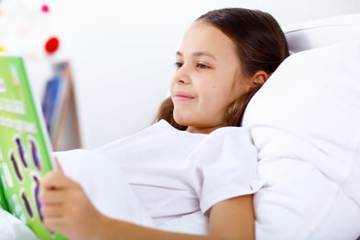 Portrait of girl with a book in bed at home