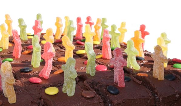 Closeup of chocolate cake decorated with jelly men, isolated on a white background
