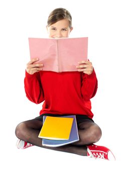 Intelligent school girl sitting with books on her lap and studying from her notebooks