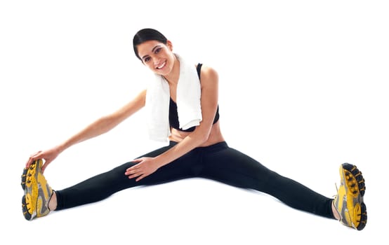 Young fit female trainer doing stretching on floor against white background