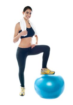 Beautiful young woman posing with one leg on fitness ball