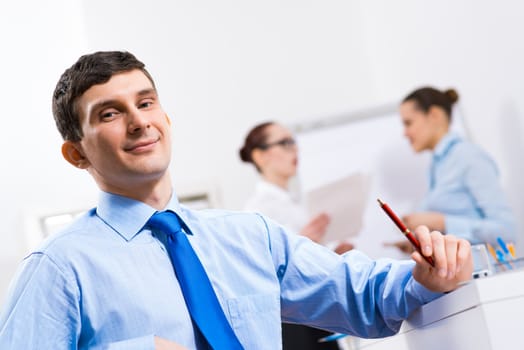 Portrait of a businessman in a blue shirt in the background of colleagues discussing