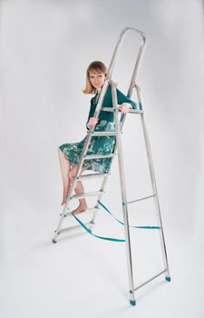 beautiful woman in a green dress sitting on a stepladder