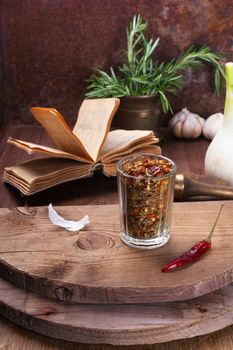 Still Life with faceted glass with a mixture of peppers and old book in the background