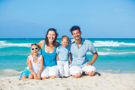 Family of four having fun on tropical beach