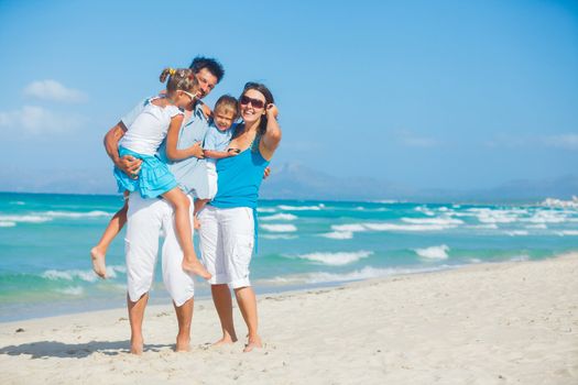 Family of four having fun on tropical beach