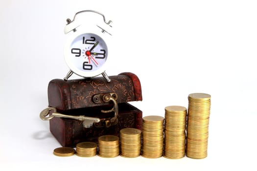 Gold alarm clock lay on money in a wooden chest