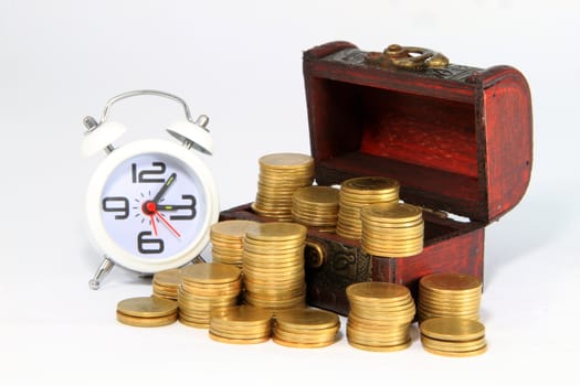 Gold alarm clock lay on money in a wooden chest