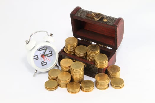 Gold alarm clock lay on money in a wooden chest