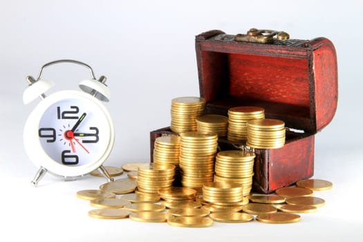 Gold alarm clock lay on money in a wooden chest