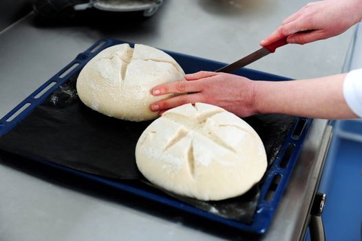 Female cutting dough in a creative manner through knife. Focus on dough