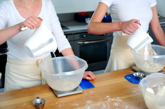 Females hand pouring water into flour bowl. Preparation for making dough