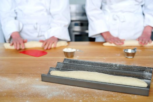 Rolling the dough on wooden table with hands. Female chefs hands