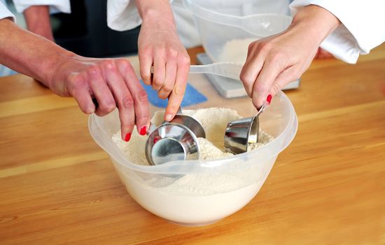 Closeup shot of females hand collecting flour from bowl