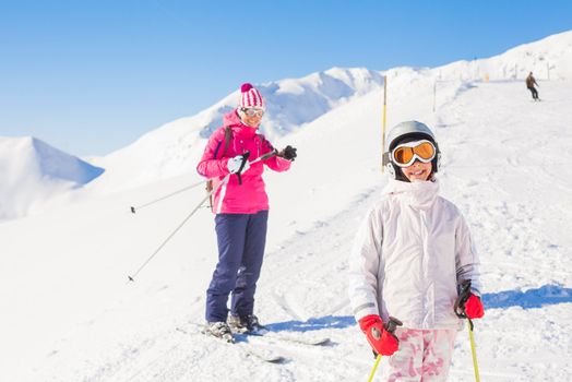 Happy smiling girl in ski goggles and a helmet with his mother, Zellertal, Austria