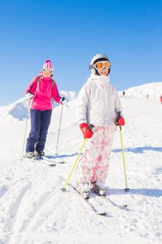 Happy smiling girl in ski goggles and a helmet with his mother, Zellertal, Austria. Vertical view