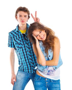 Smiling teenager boy indulge his pretty girlfriend. Isolated on white background.