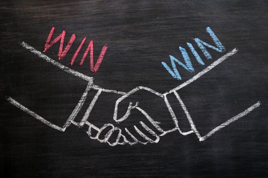 Mutual benefit or win-win concept of handshaking drawn with chalk on a blackboard