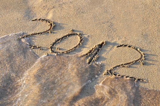 2012 written on sand, being washed out by sea