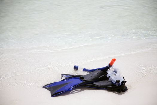 Snorkeling tube, mask and fins on a beach with waves lapping.