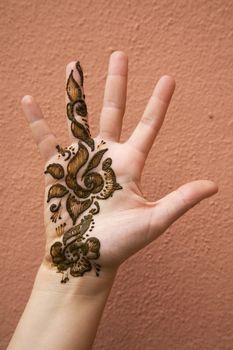 Henna applied on hand against a backdrop of a red wall.







Henna on hand