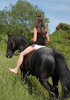 young riding girl on her black stallion in undergarment