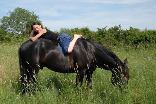 young woman and her black stallion in a field