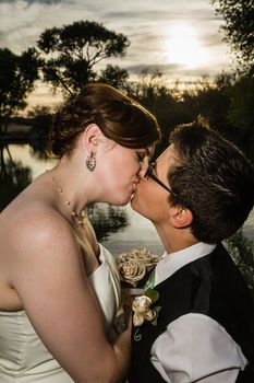 Loving same sex married couple kissing near lake