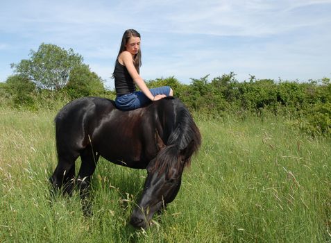 young woman and her black stallion in a field