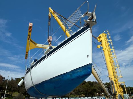 sailboat hanging on crane in harbor service