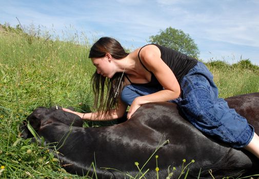 young riding girl and her black stallion laid down