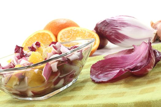 fresh red chicory salad with orange slices and dressing on a napkin