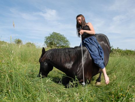 young riding girl and her black stallion laid down