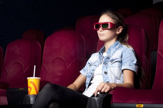 young woman sitting alone in the cinema and watching a movie