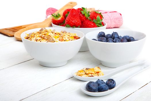 fresh blueberry, strawberry and corn flakes in white porcelain bowl, wooden table